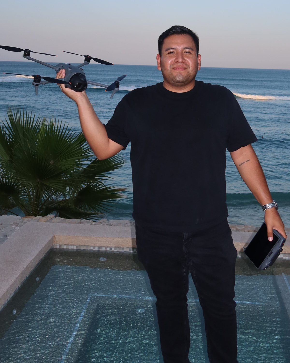 Roberto Barajas holding a drone above the ocean in Los Cabos